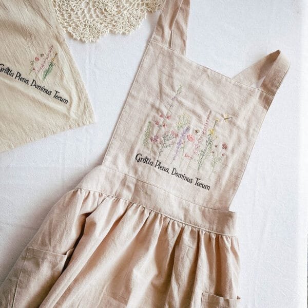 Catholic lifestyle gifts collection featuring embroidered kitchen apron and napkin set